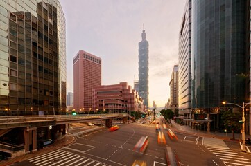 Wall Mural - Cityscape of Downtown Taipei, the capital city of Taiwan, with 101 Tower & World Trade Center standing in XinYi Financial District at sunrise and cars dashing thru the intersection in morning twilight