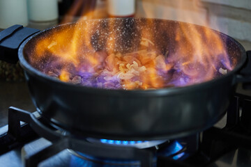 Poster - Beef meat fried with onions in frying pan, flambe on gas stove