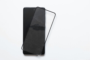 Phone and broken protective glass lies nearby on a white background, replacement of protective glass