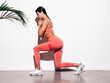 © halayalex - Tanned fitness woman in pink sports clothing. Sexy young beautiful model with perfect body.Female isolated on white background in studio. Stretching out before training. Near wall. Making lunges