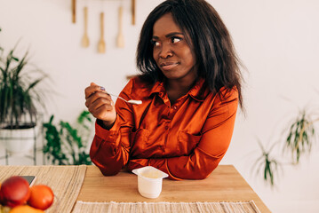 Wall Mural - Beautiful young woman eating yogurt in the kitchen in the morning. Healthy food. Close up. Portrait shot