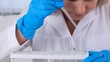 © Евгения Медведева - professional scientist takes a sample for a medical experiment. A research chemist works in a laboratory with a micropipette and a microscope