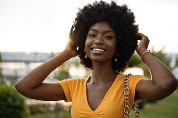 Wall Mural - Portrait of a young african american woman smiling standing at the city.