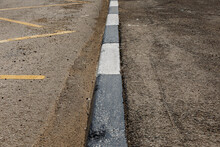 Concrete Curb. Street Border Painted In White And Black.