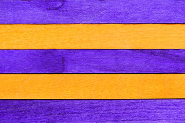 Wall Mural - Alternating Purple and Orange Painted Boards for a Halloween Background. Two-tone striped wooden textured background. Horizontal wooden boards divided into orange and purple for your scary creativity.