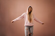 © Halfpoint - Fashion studio portrait of a happy young blonde woman in hoodie posing over pink background.