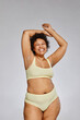 © Seventyfour - Vertical portrait of carefree black woman wearing underwear and laughing happily against grey background