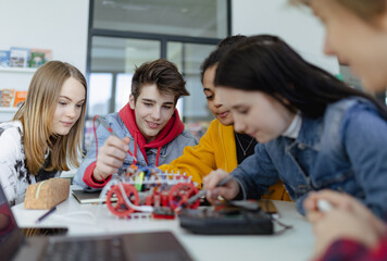 Wall Mural - group of high school students building and programming electric toys and robots at robotics classroo