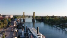 Aerial Wide Shot Flying Over The Delta King Steamboat Towards Tower Bridge On The Sacramento River. 4K