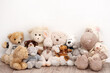 Many soft toys are sitting on the background of a white wall