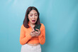 © Reezky - A portrait of a sad Asian woman looking at her smartphone over blue background