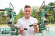 © Евгений Шемякин - portrait of handsome happy strong athletic man athlete bodybuilder training outdoors at open air gym machine at summer, gain hands and shoulders muscles. Bodybuilding and fitness, healthy lifestyle