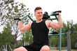 © Евгений Шемякин - portrait of handsome happy strong athletic man athlete bodybuilder training outdoors at open air gym at summer, gain hands and shoulders muscles. Bodybuilding and fitness, healthy lifestyle