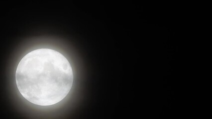 Wall Mural - Glowing huge full moon as seen from earth through the clouds against starry night sky. Large full moon moves across the sky, moon makes its way from bottom left frame to top right.