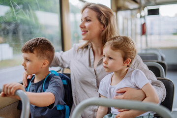 Wall Mural - Young mother with little kids travelling in tram in summer, commuting and sustainable lifestyle concept.