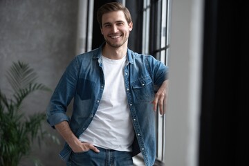 Image of a positive smiling young man indoors at home looking camera