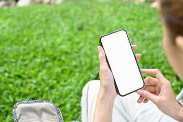 close-up, beautiful young asian woman using a smartphone in the green park.