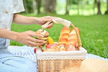 Close-up, A Female Sits On Picnic Blanket And Holding A Dessert Pastries Wicker Basket.