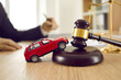 © Studio Romantic - Little red toy automobile on table with sound block and gavel. Small car model on wooden desk with judge's hammer. Car accident, drunk driving, lawsuit, court of law, justice, lawyer services concept