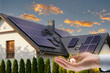 The concept of saving money and clean energy. Solar panel on the roof of a modern house and coins in hand.