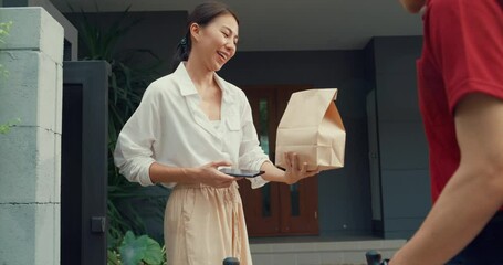 Wall Mural - Young happy Asian woman accept paper bag from delivery man with bicycle in red uniform carry case box scan QR code payment on smartphone in front of house. express food delivery concept.