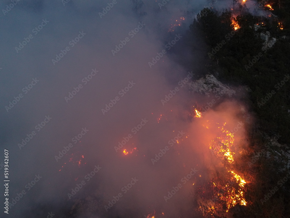 Aerial panoramic view of a forest fire at night, heavy smoke causes air ...