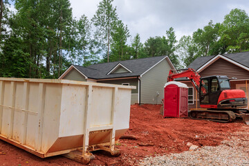 Wall Mural - An industrial dumpster rubbish removal containers on the ground beneath a house in construction site