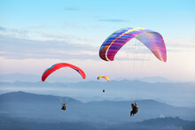 Paragliding In The Sky. Paraglider  Flying Over Landscape Sun Set Concept Of Extreme Sport,