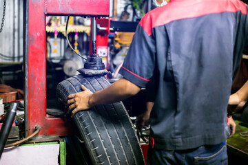 Selective focus to car tire patch machine with blurry mechanic working in car service center.