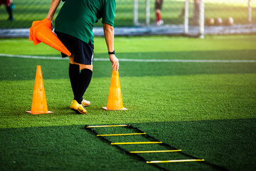 Wall Mural - Coach is putting the marker cones for soccer training to run and jump.