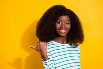 Canvas Print - Photo of cheerful pretty girl direct thumb finger empty space promotion isolated on yellow color background