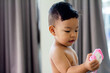 Cute undressed baby with toys, holding toys looking at camera. slective focus