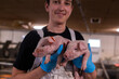 © andrewsh.ca - A farm worker in a special white uniform and blue gloves holds and hugs two piglets and looks at the camera at an industrial factory