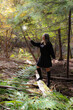 Young woman holding and looking in amazement at a magic wand throwing off light from it's tip, in the autumn woods to cast a spell