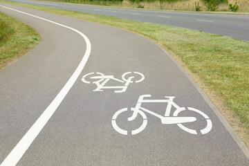 Wall Mural - Bicycle lane with white sign painted on asphalt near sidewalk