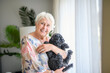 © Louis-Paul Photo - cute senior woman with poodle on the living room