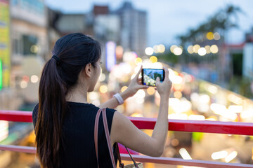 Wall Mural - Woman take photo on cellphone in street market