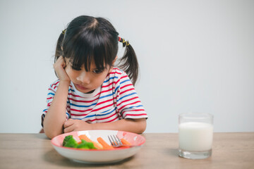 Nutrition & healthy eating habits for kids concept. Children do not like to eat vegetables. Little cute girl refuses to eat healthy vegetables.