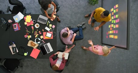 Poster - Overhead view of creative team in a meeting brainstorming ideas. Professional colleagues working together to plan a solid marketing strategy. Group in close collaboration inside boardroom