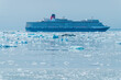 A view across the floating ice of Disenchartment Bay towards a cruise ship in Alaska in summertime