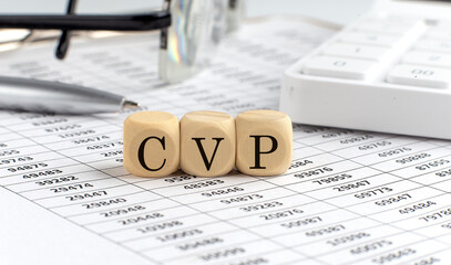 wooden cubes with the word CVP Cost Volume Profit on a financial background with chart, calculator, pen and glasses, business concept.