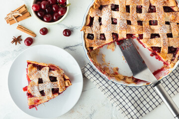 Wall Mural - Delicious homemade cherry pie with Flaky Crust sprinkled with powdered sugar on the white marble background. American traditional pastry. Flat lay. Fresh summer berry tart dessert