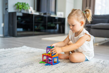 Little Girl Playing Colorful Magnet Plastic Blocks Kit At Home. The Child Playing Educational Games. Early Childhood Development.