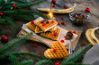 Homemade Belgian waffles heart shaped on plate with colorful red sweet cherry berries, banana, and boiled condensed milk,flaming bengal fire. Christmas new year background,dessert food