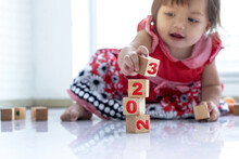 Close Up Hands Of Child Baby Girl Play Wooden Block, Try Stacking 2023 Wooden Cube Blocks On Floor, Selective Focus