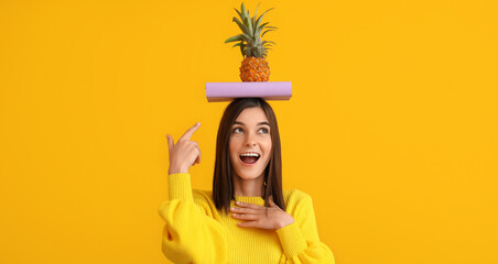 Wall Mural - Beautiful happy young woman with book and pineapple on yellow background