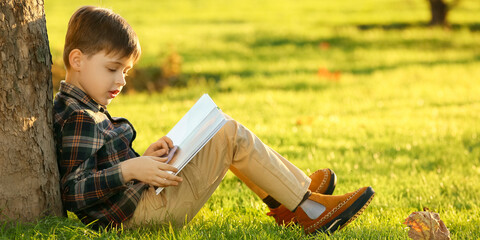 Sticker - Cute little boy reading book in park