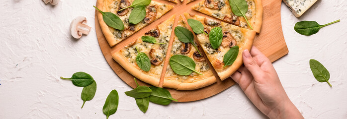 Wall Mural - Female hand taking slice of tasty pizza from wooden board, top view