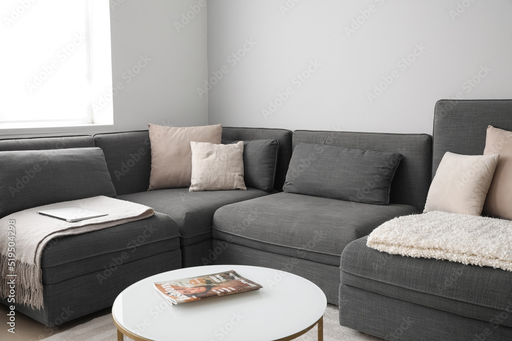 Comfortable black sofa with cushions in living room