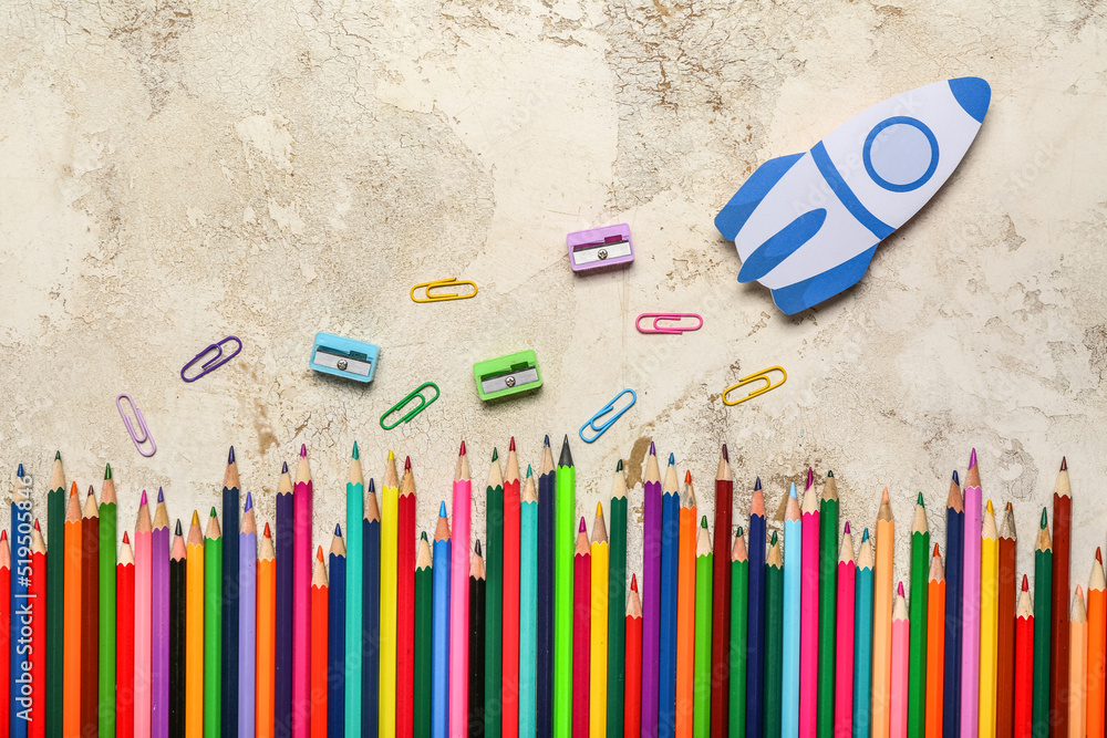 Paper rocket with school stationery on light background